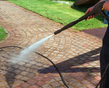Cleaning street with high pressure power washer, washing stone garden paths